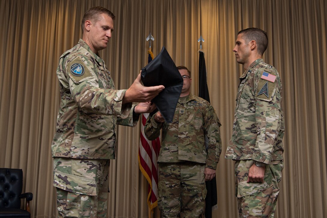 Military men in uniform unsheathing a guidon