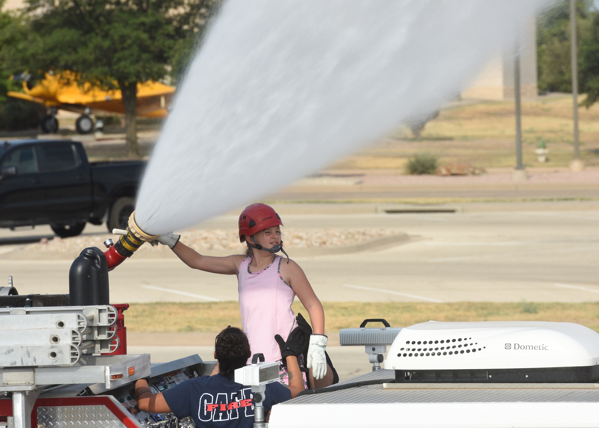 Gretchen Volk, junior firefighter camp student, operates a fire truck water cannon, at Goodfellow Air Force Base, Texas, July 14, 2022. Volk manually changed the spray pattern of the cannon from narrow to wide with the assistance of 17th Civil Engineer Squadron firefighters. (U.S. Air Force photo by Airman 1st Class Zachary Heimbuch)