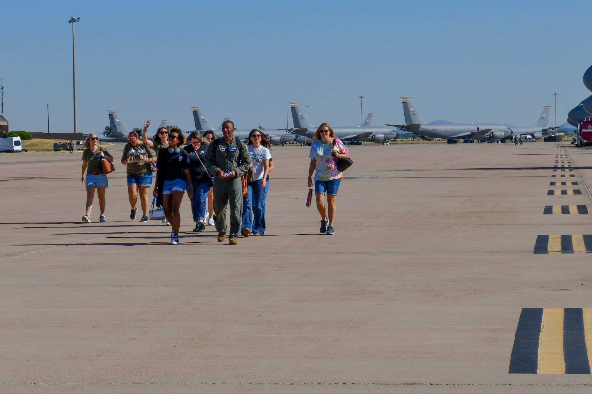 U.S. Air Force Capt. Ryan Smith, 56th Air Refueling Squadron instructor pilot, escorts spouses from the 97th Air Mobility Wing to a KC-46 Pegasus at Altus Air Force Base, Oklahoma, July 11, 2022. The spouses participated in an orientation flight to experience aerial refueling. (U.S. Air Force photo by Airman 1st Class Miyah Gray)