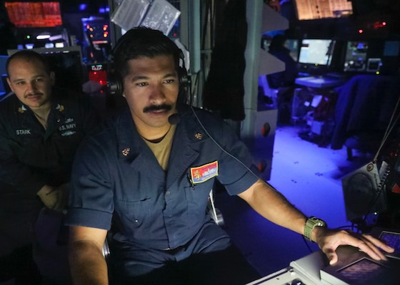 Chief Fire Controlman (Aegis) Ralph Salas, right, from Palm Springs, California, and Electronics Technician 1st Class Christopher Stark, left, from Corapeake, North Carolina, monitor surface contacts from the combat information center as the guided-missile destroyer USS Benfold (DDG 65) conducts a freedom of navigation operation near the Spratly Islands. Benfold is forward-deployed to the U.S. 7th Fleet area of operations in support of a free and open Indo-Pacific.