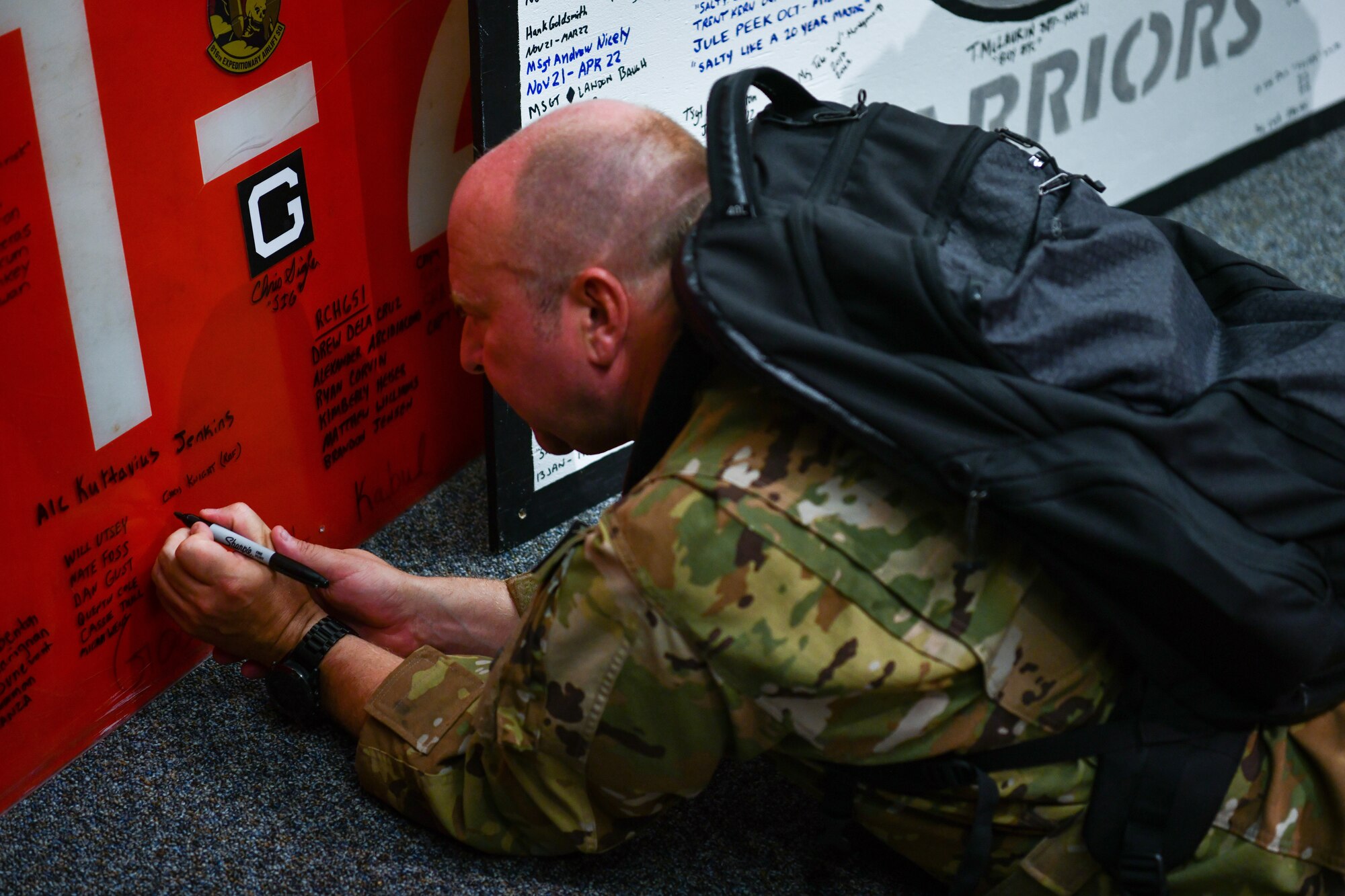 Royal Air Force Capt. Christopher Knight, 14th Airlift Squadron pilot, signs a runway panel from Afghanistan that was used during Operation Allies Refuge at the Air Force Museum in Dayton, Ohio, July 11, 2022.