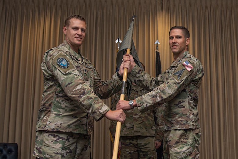 Two men in military uniforms holding a guidon