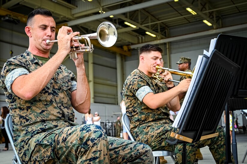 U.S. Marines assigned to Marine Aircraft Group 49 play instruments as part of a band in preparation for a change of command ceremony on July 16, 2022 at Joint Base McGuire Dix Lakehurst. The change of command ceremony is a military tradition that represents a formal transfer of authority and responsibility for a unit from one officer to another. The mission of MAG 49 is to organize, train, and equip combat ready squadrons to augment and reinforce the active Marine forces in time of war, national emergency, or contingency operations, and to provide personnel and assault support capabilities to relieve operational tempo for active duty forces. (U.S. Air Force Photo by Senior Airman Matt Porter)