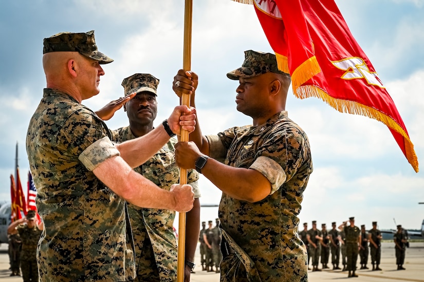 U.S. Marine Corps Col. Lonnie Cobb, Marine Aircraft Group 49 commander, passes a flag to Marine Corps. Col. Russel Rybka during a change of command ceremony on July 16, 2022 at Joint Base McGuire Dix Lakehurst. The change of command ceremony is a military tradition that represents a formal transfer of authority and responsibility for a unit from one officer to another. The mission of MAG 49 is to organize, train, and equip combat ready squadrons to augment and reinforce the active Marine forces in time of war, national emergency, or contingency operations, and to provide personnel and assault support capabilities to relieve operational tempo for active duty forces. (U.S. Air Force Photo by Senior Airman Matt Porter)