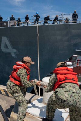 Fireman Wai Yan Han, left, and Retail Specialist Seaman Britany Cooper, assigned to the Wasp-class amphibious assault ship USS Bataan (LHD 5), release the mooring line from the bollard on the pier as the Arleigh Burke-class guided-missile destroyer USS Nitze (DDG 94) deploys from Naval Station Norfolk, July 17.