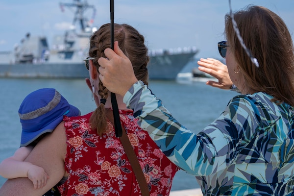 Family members wave goodbye to their Sailors as the Arleigh Burke-class guided-missile destroyer USS Nitze (DDG 94) deploys from Naval Station Norfolk, July 17