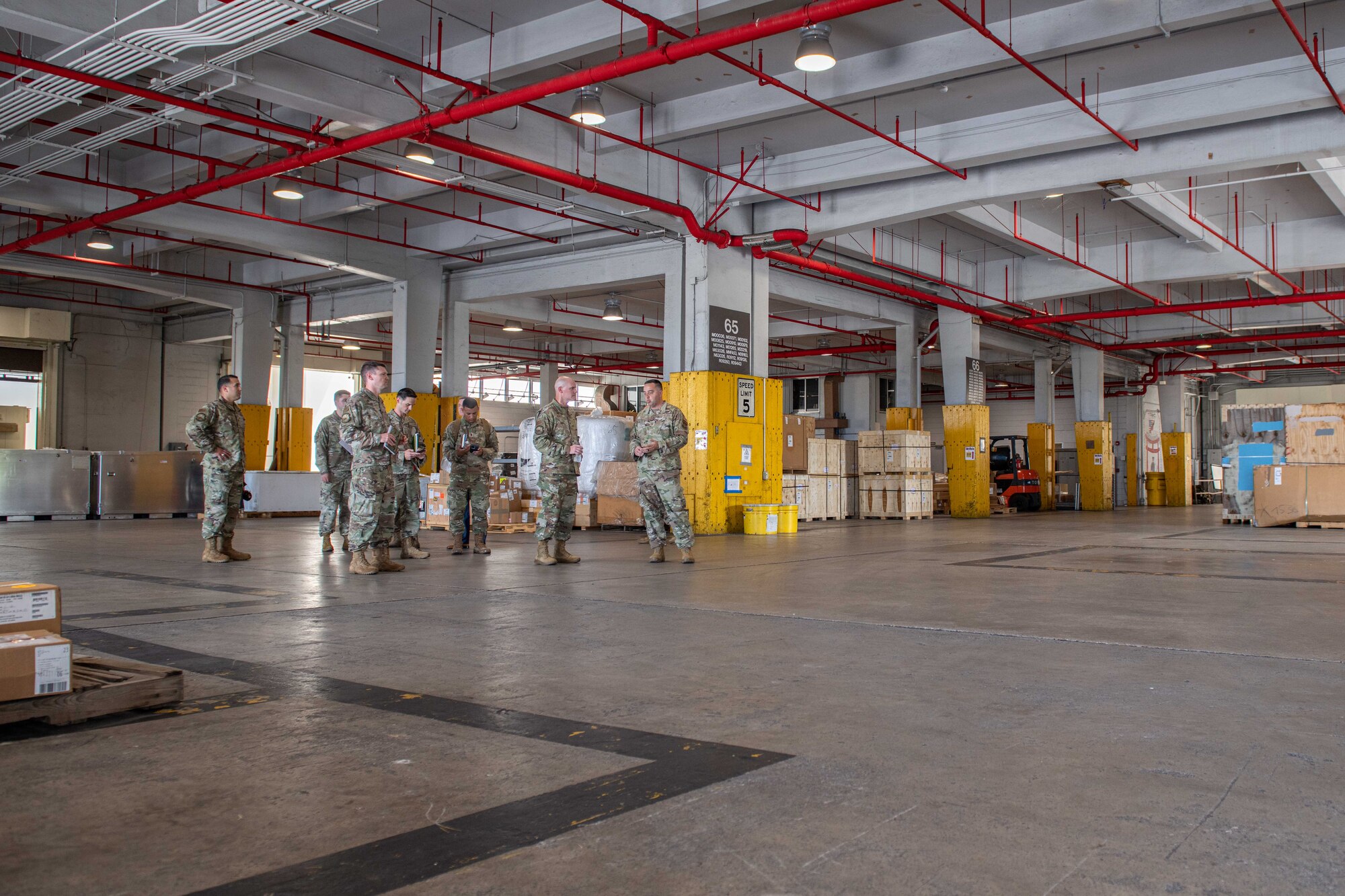 A group of Airmen tour a warehouse where packages are stored and transported