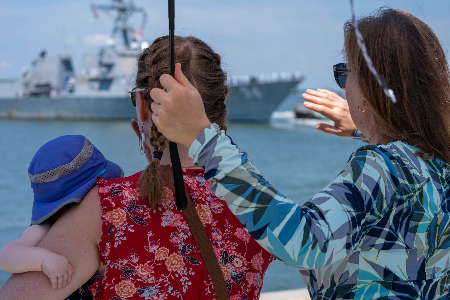 Family members wave goodbye to their Sailors as the Arleigh Burke-class guided-missile destroyer USS Nitze (DDG 94) deploys from Naval Station Norfolk, July 17