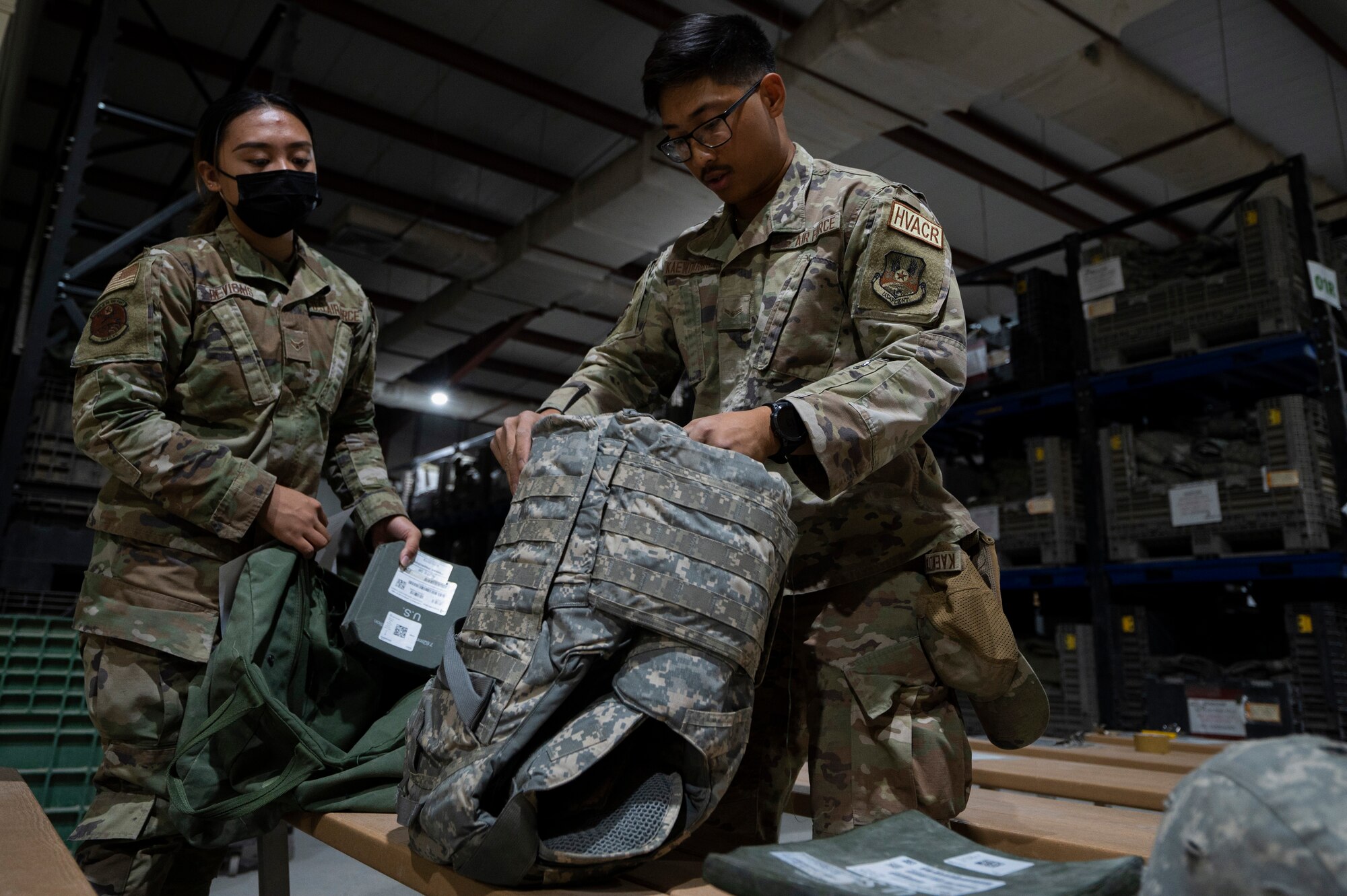 U.S. Air Force Airman 1st Class Alezen Devicais, 386th Expeditionary Logistics Readiness Squadron Expeditionary Theater Distribution Center technician, assists Airman 1st Class Atichai Kaewdarunee, 386th Expeditionary Civil Engineering Squadron HVAC technician, with turning in his issued equipment at the ETDC on Ali Al Salem Air Base, Kuwait, July 13, 2022. The 386th LRS/ETDC team were recently able to reduce customer wait times by 30 minutes by prepacking the necessary gear that each military member requires, ahead of time. (U.S. Air Force photo by Staff Sgt. Dalton Williams)