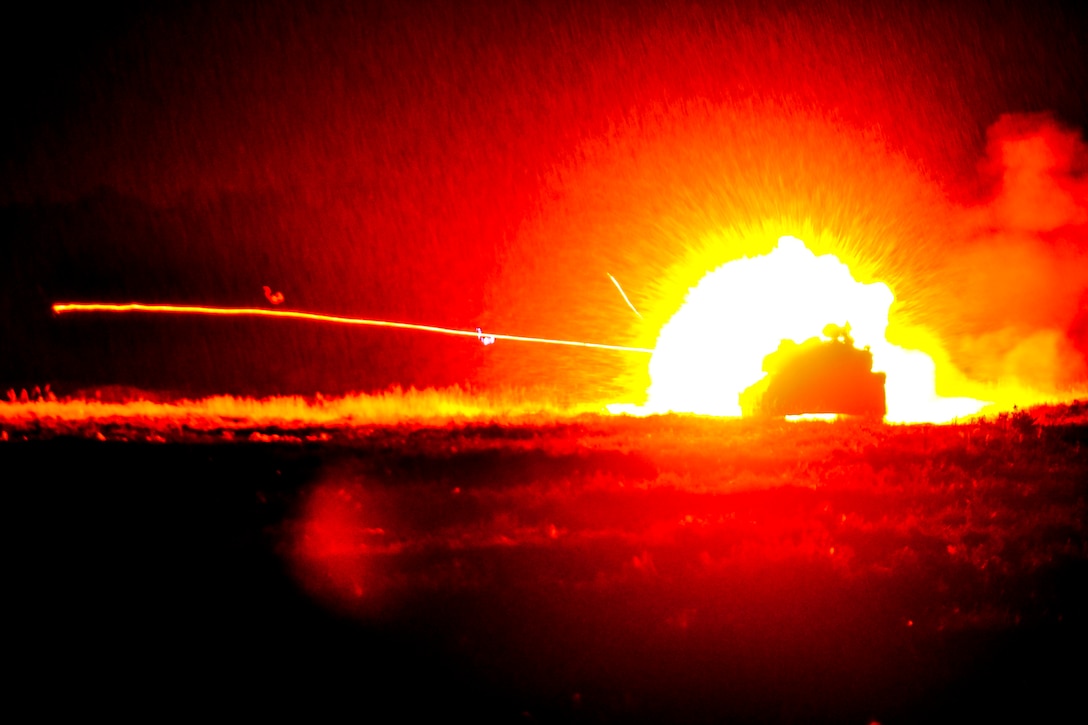 Weapons fire from a tank lights the night sky.