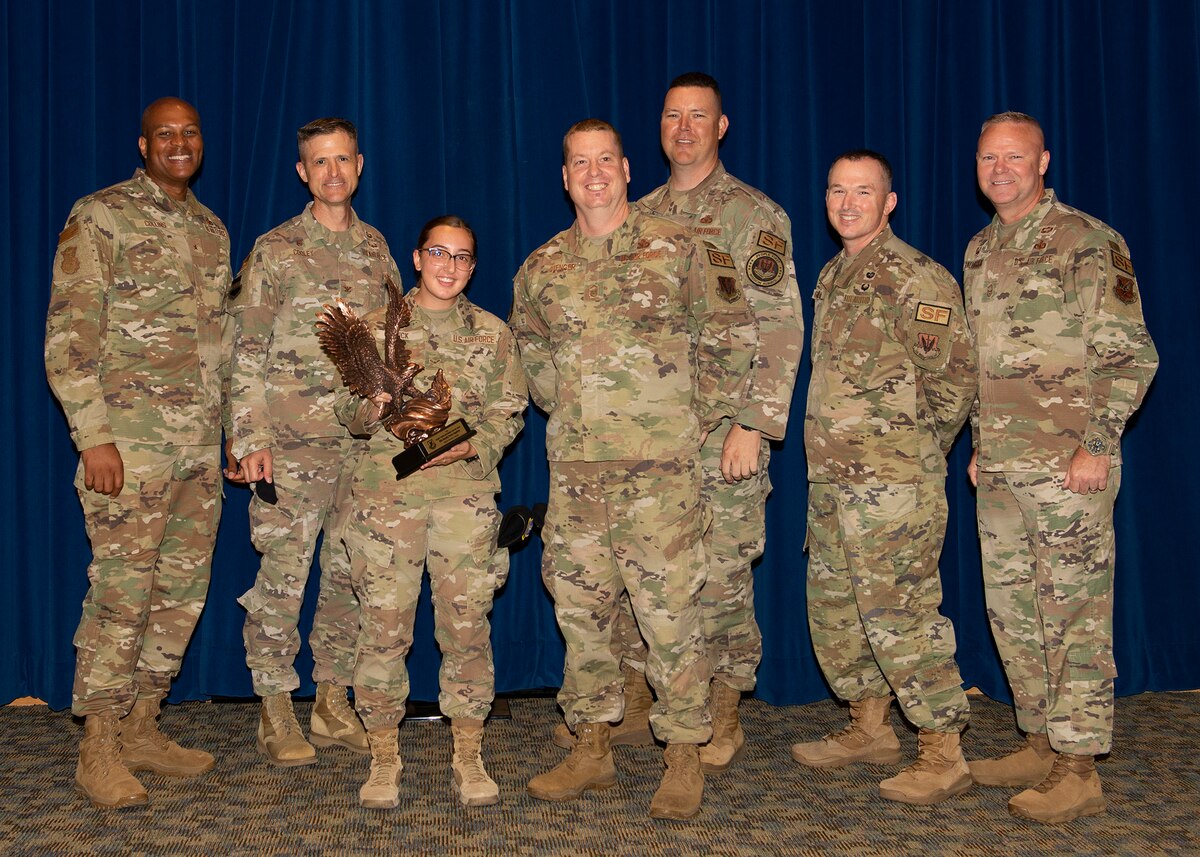 seven Airmen posing for group photo, one person holding a trophy of eagle in her hands