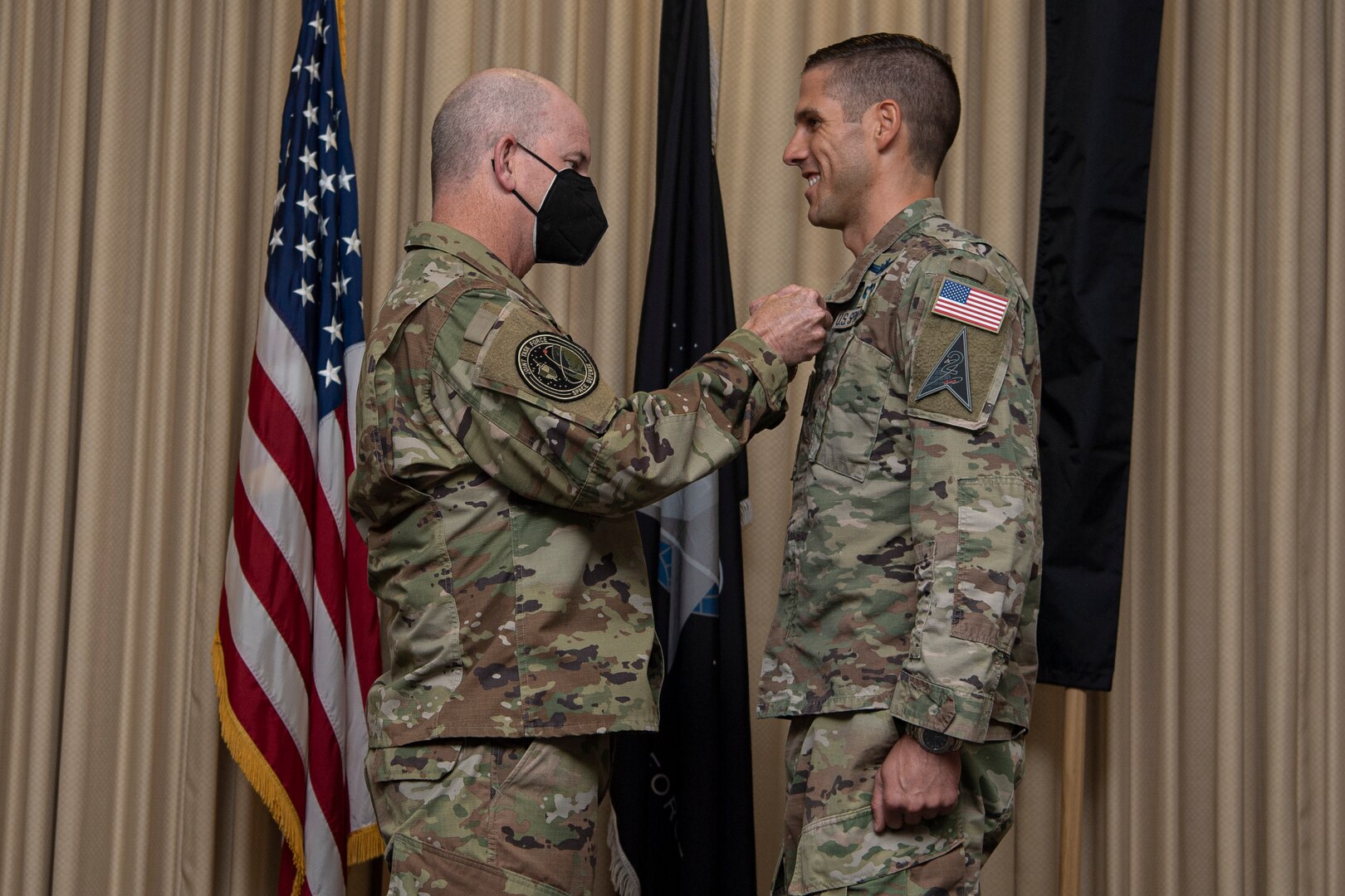 Military man in uniform pinning medal onto another military man in uniform
