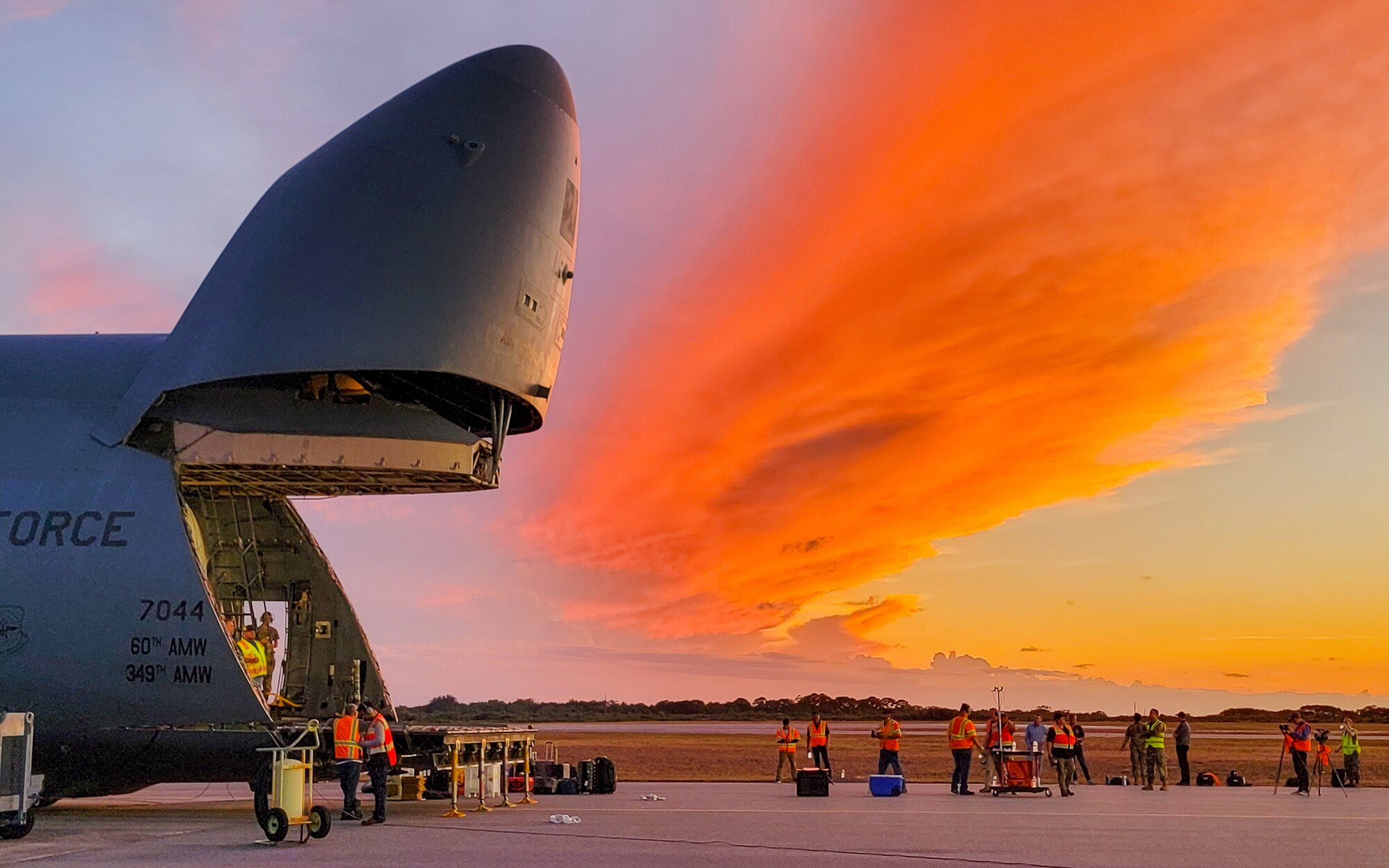 A large military aircraft is being loaded by a large white container.