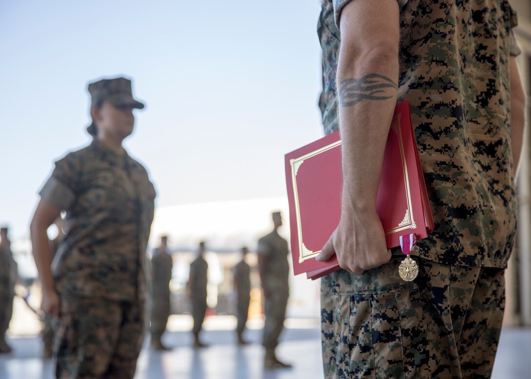 U.S. Marine Corps Sgt. Maj. Jon Osborn, squadron sergeant major, Marine Aviation Logistics Squadron 13 (MALS-13), 3rd Marine Aircraft Wing, stands with a Meritorious Service Medal prior to its presentation to Master Sgt. Maribel Valdez during her retirement ceremony at Marine Corps Air Station Yuma, Arizona, June 24, 2022.