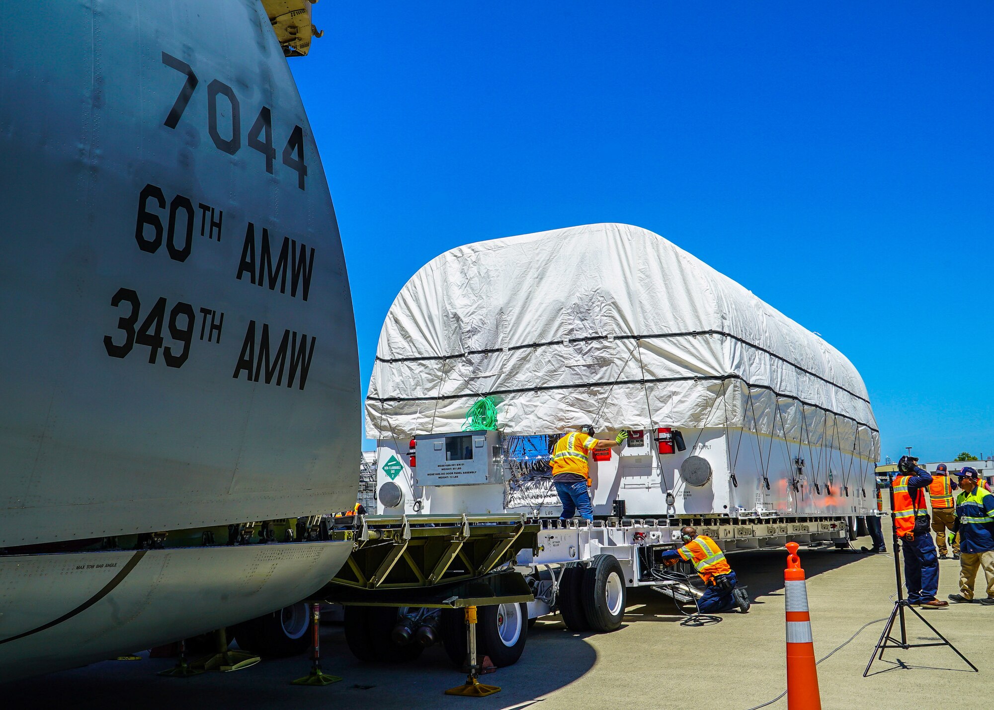 A large military air craft is loaded with a large white container.