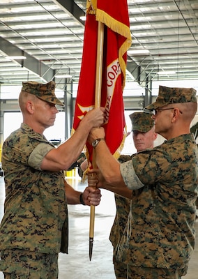 Maj. Gen. Joseph F. Shrader, right, out-going commanding general, Marine Corps Logistics Command, passes the unit colors to Maj. Gen. Keith D. Reventlow, left, as he assumes command of MARCORLOGCOM