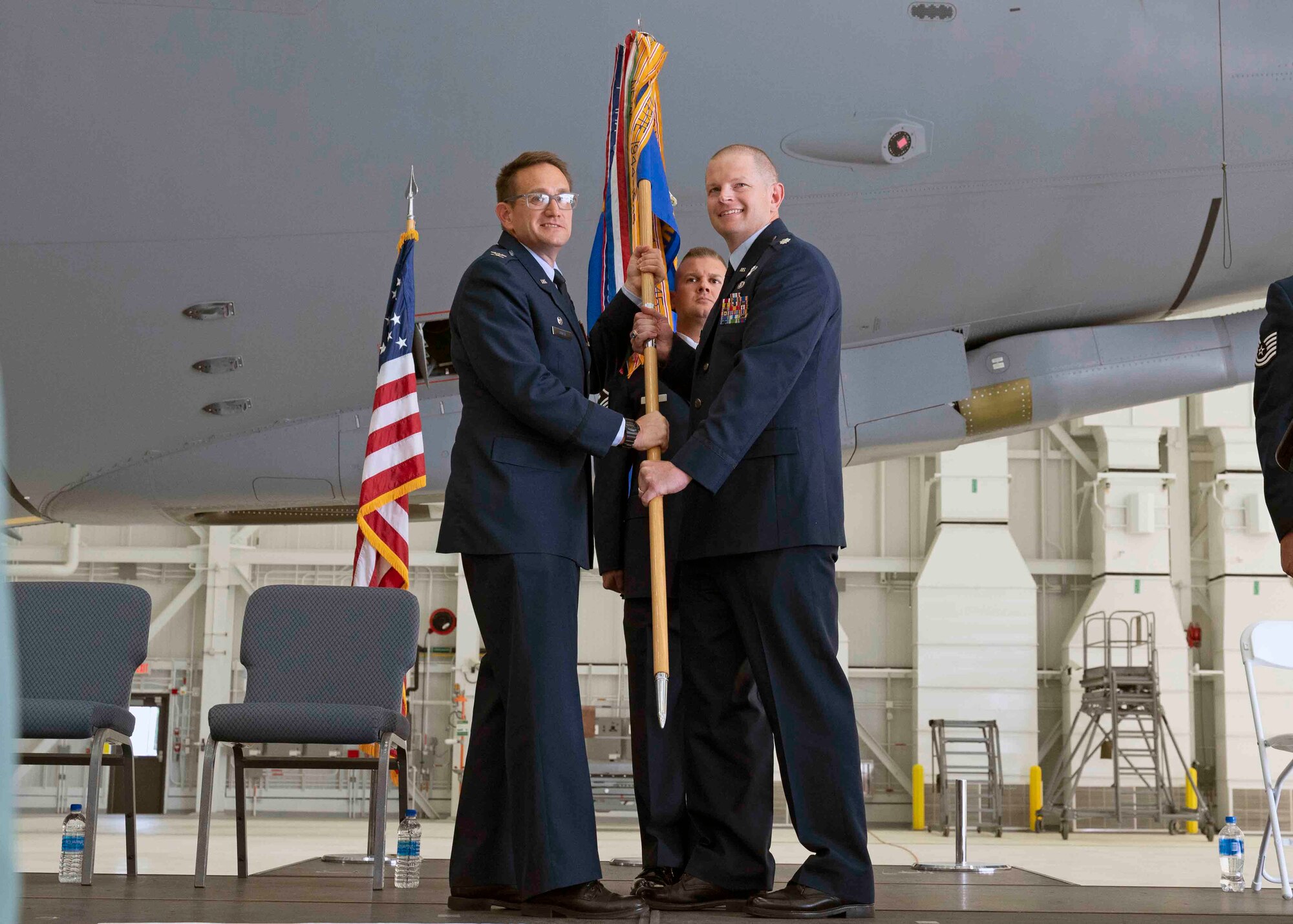 Col. Joshua Zaker, commander, 22nd Operations Group, McConnell Air Force Base, passes the 64th Air Refueling Squadron unit guidon to Lt. Col. Brandon Stock, incoming commander.