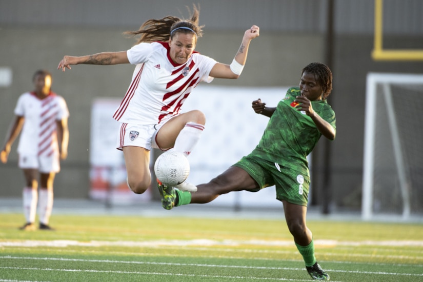 Two female soccer players compete on the field.