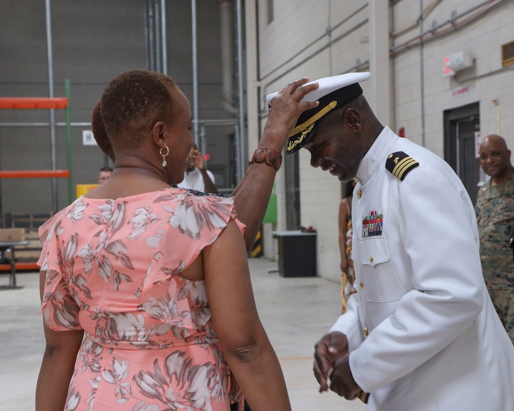 U.S. Navy Cmdr. Devon Foster, right, chaplain, Marine Aircraft Group 13 (MAG-13), 3rd Marine Aircraft Wing, has his cover placed by family during his promotion ceremony at Marine Corps Air Station Yuma, Arizona, June 29, 2022.