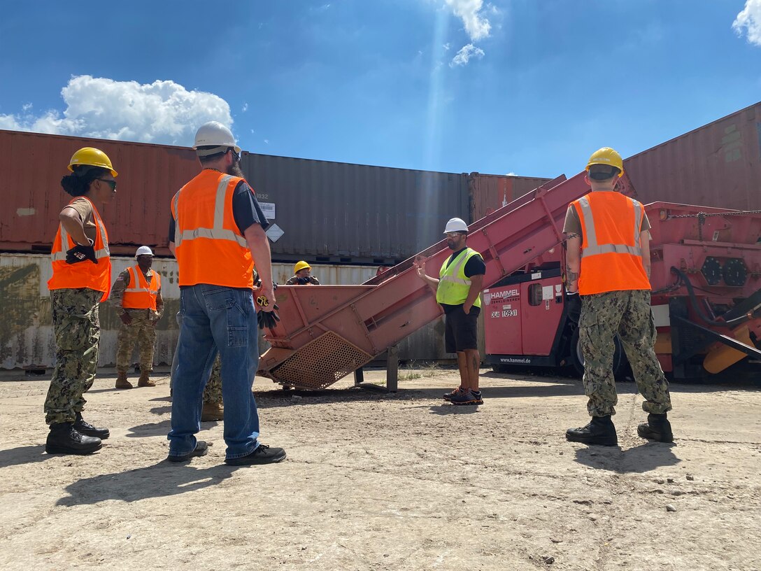 Group of men and woman standing next to shredder equipment