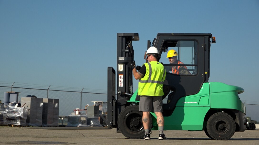 Man guides woman operating a forklift