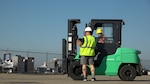 Man guides woman operating a forklift