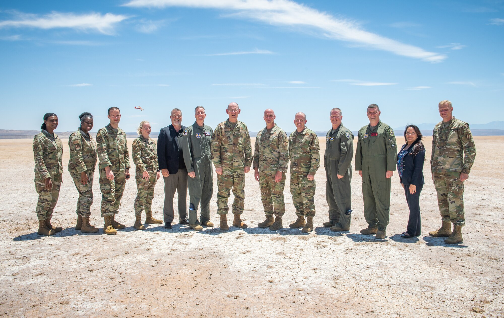 412th Test Wing leadership pose for a group photo with Gen. Duke Z. Richardson, Air Force Materiel Command commander, while a sUAS (small Unmanned Aerial System) flies above Rogers Dry Lake Bed on Edwards Air Force Base, California, July 13. (U.S. Air Force photo by James West)