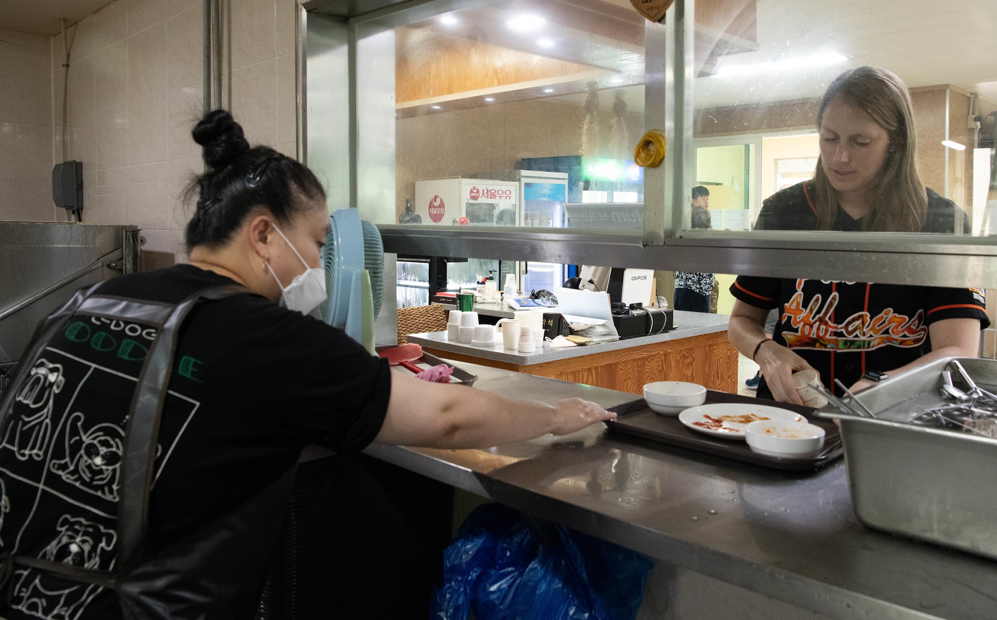 A Gun Sung Maru worker takes a food tray from Master Sgt. Sandra Welch, 8th Fighter Wing Public Affairs superintendent, at Kunsan Air Base, Republic of Korea, July 8, 2022. Gun Sung Maru provided traditional Korean meals to many Wolf Pack service members. (U.S. Air Force photo by Staff Sgt. Sadie Colbert)
