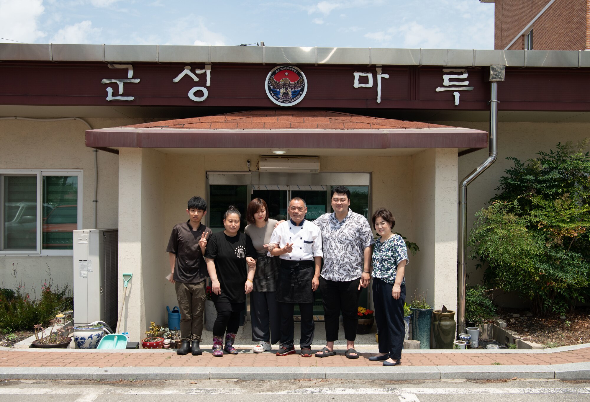 Gun Sung Maru workers smile in front of their restaurant at Kunsan Air Base, Republic of Korea, July 7, 2022. After serving the Wolf Pack for five years, Gun Sung Maru closed permanently with hopes of reopening their restaurant outside of Kunsan AB. (U.S. Air Force photos by Staff Sgt. Sadie Colbert)