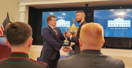 A representative from the office of the White House National Cyber Director, left, presents Jakob Kreuze, a PALACE Acquire computer scientist in the Command, Control, Communications, Intelligence and Networks Directorate's Special Programs Division, with a first place award for the offense track of the 2021 President's Cup Cybersecurity Competition during a ceremony at the White House, July 15.