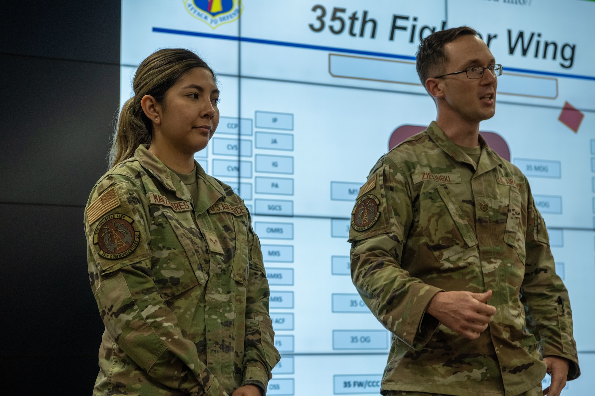 People in uniform attend a briefing indoors while people are recognized
