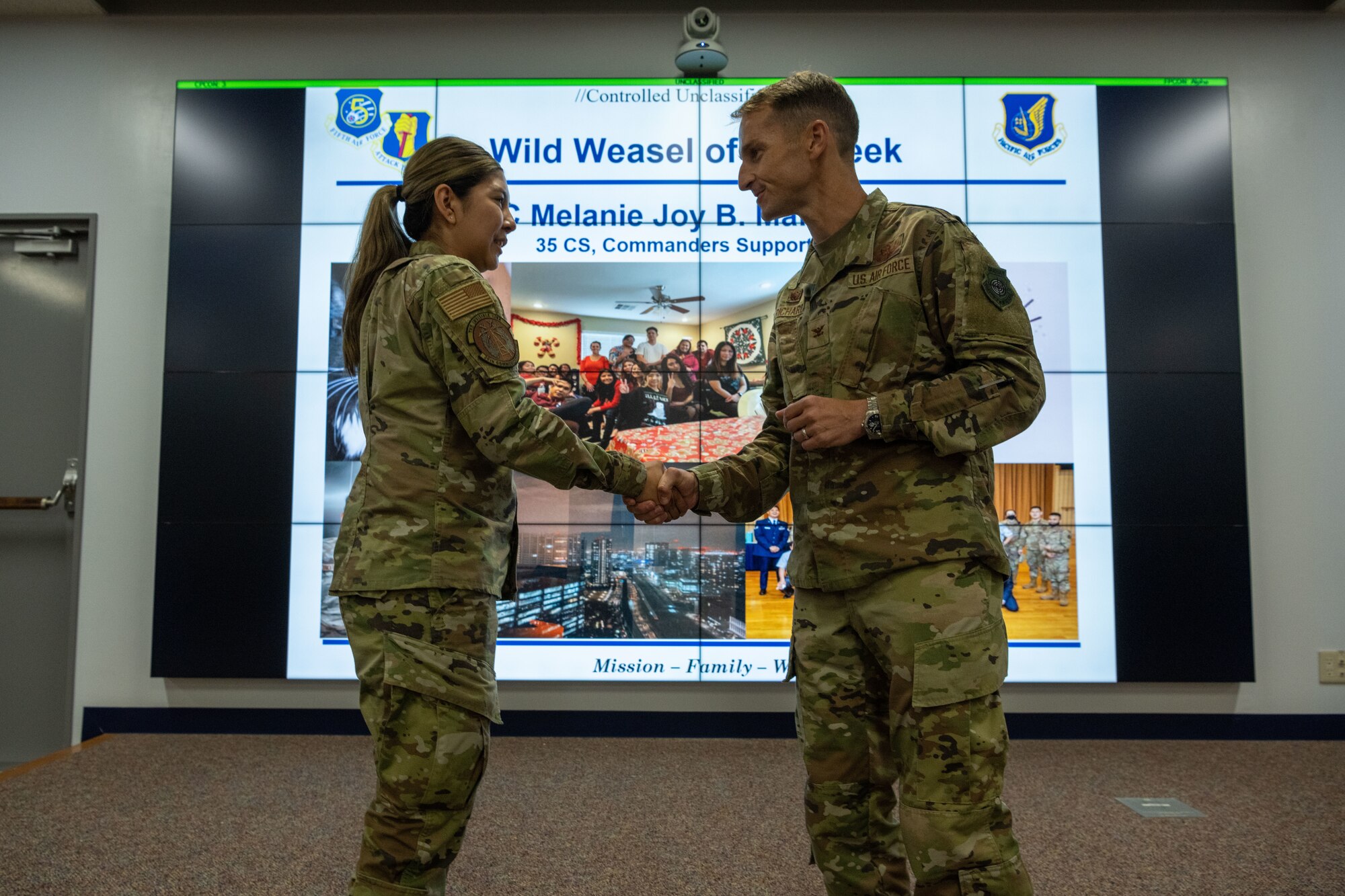 People in uniform attend a briefing indoors while people are recognized