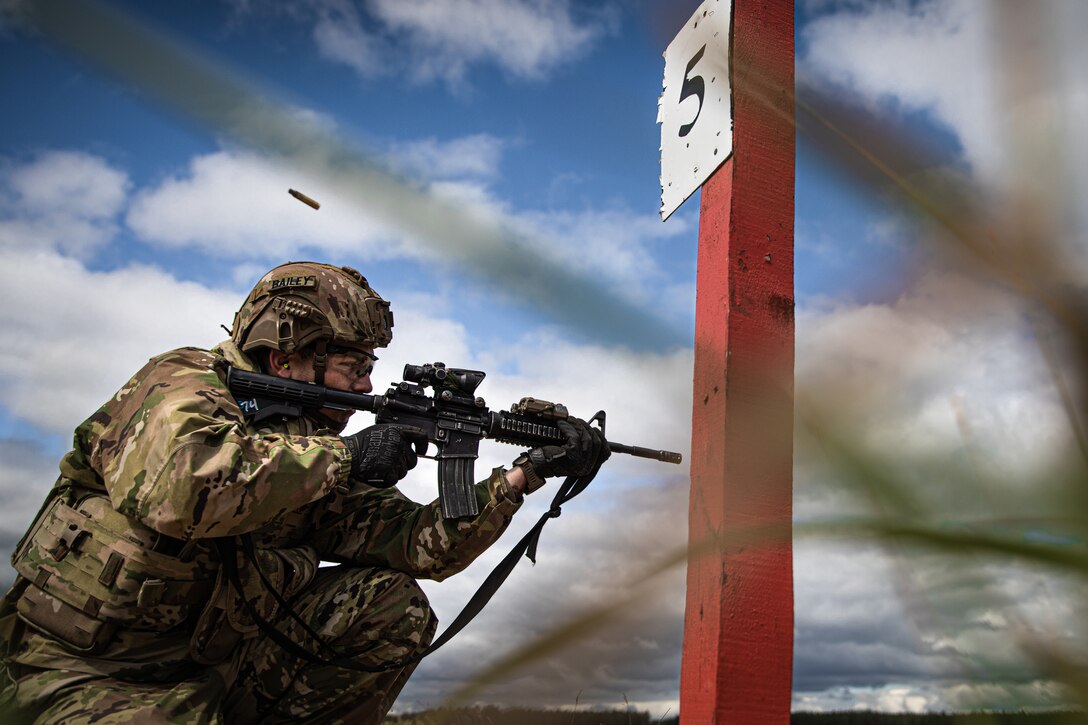 A kneeling soldier fires a weapon.