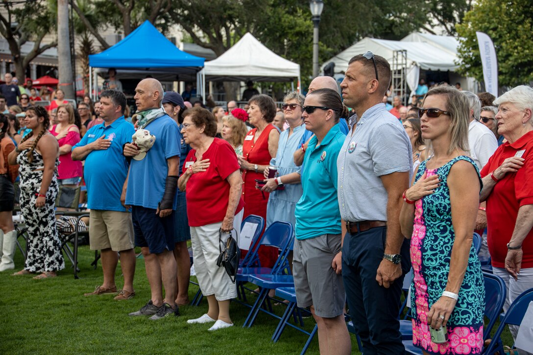U.S. Marines, Sailors and civilians stand for the National Anthem at the 66th Annual Beaufort Water Festival in downtown Beaufort, S.C., July 15, 2022. The Beaufort Water Festival is an annual event that brings the locals together to celebrate the community. (U.S. Marine Corps photos by Cpl. Aidan Parker)