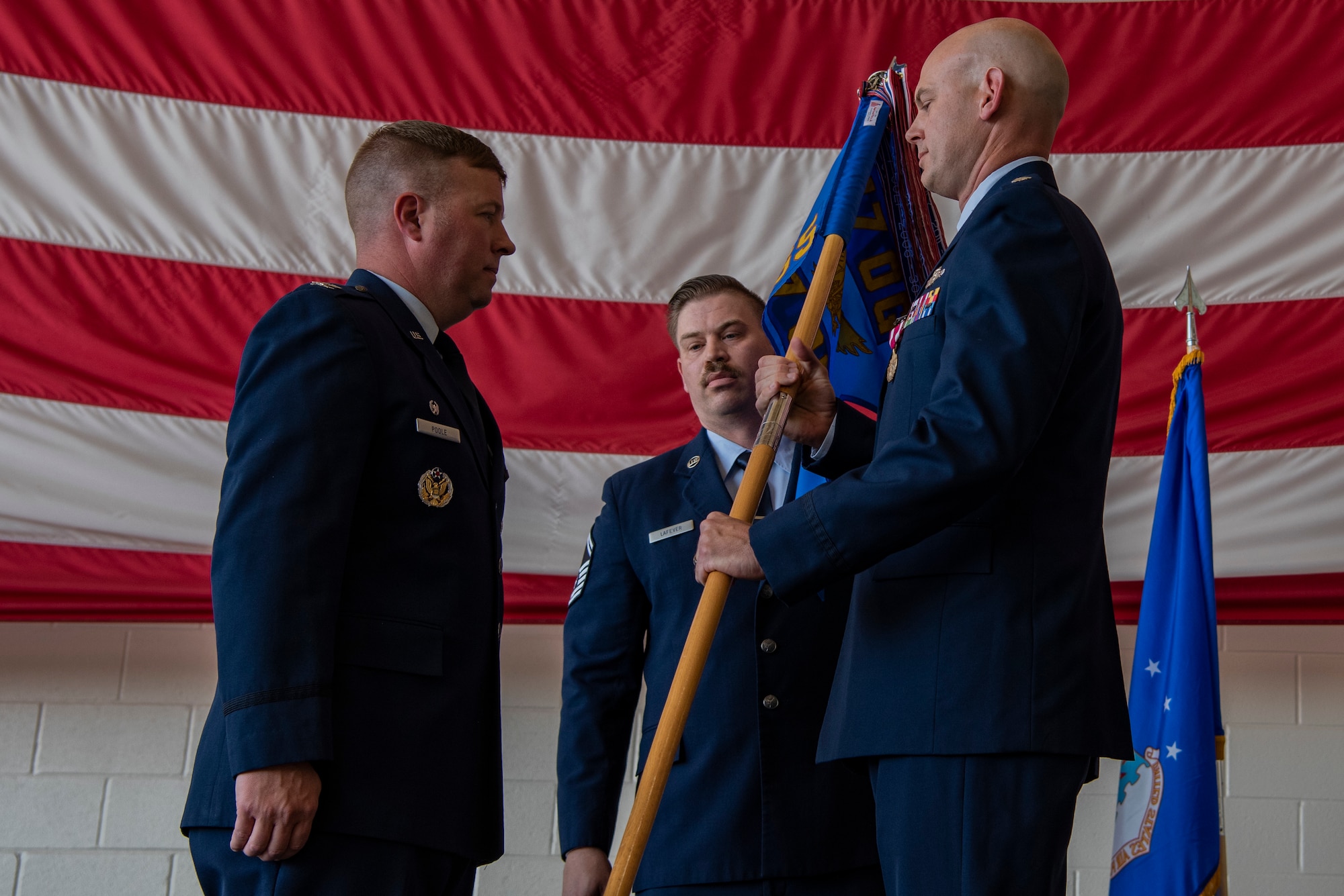 Lt. Col. Brenton Gaylord, outgoing 317th Operations Support Squadron commander, right, takes the guidon from Col. John Poole, 317th Operations Group commander, left, during the 317th OSS change of command ceremony at Dyess Air Force Base, Texas, June 30, 2022. The 317th OSS has approximately 130 personnel who oversee organizing, training and equipping the aircrews of the 317th Airlift Wing. (U.S. Air Force photo by Airman 1st Class Ryan Hayman)