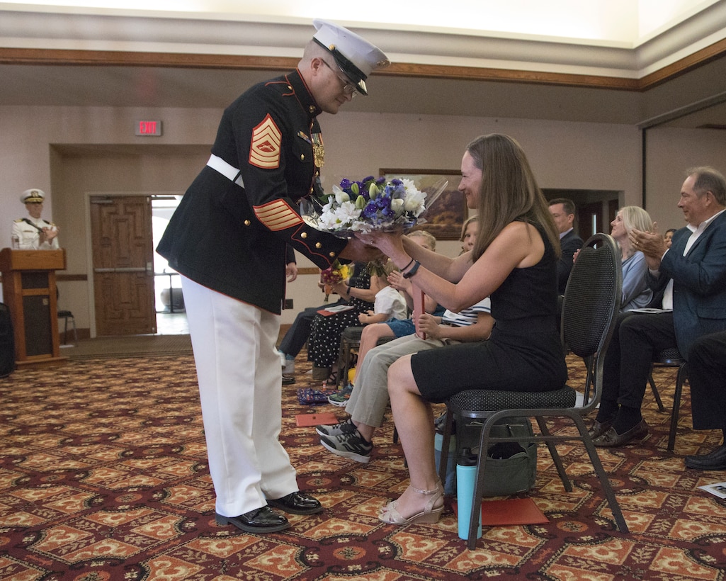 U.S. Marine Corps Master Sgt. Michael Hodge, chief, Installation and Logistics (I&L), Marine Corps Air Station Yuma, Arizona, gives flowers to Megan Montgomery during Cmdr. Gareth Montgomery’s retirement ceremony aboard the installation, July 11, 2022.