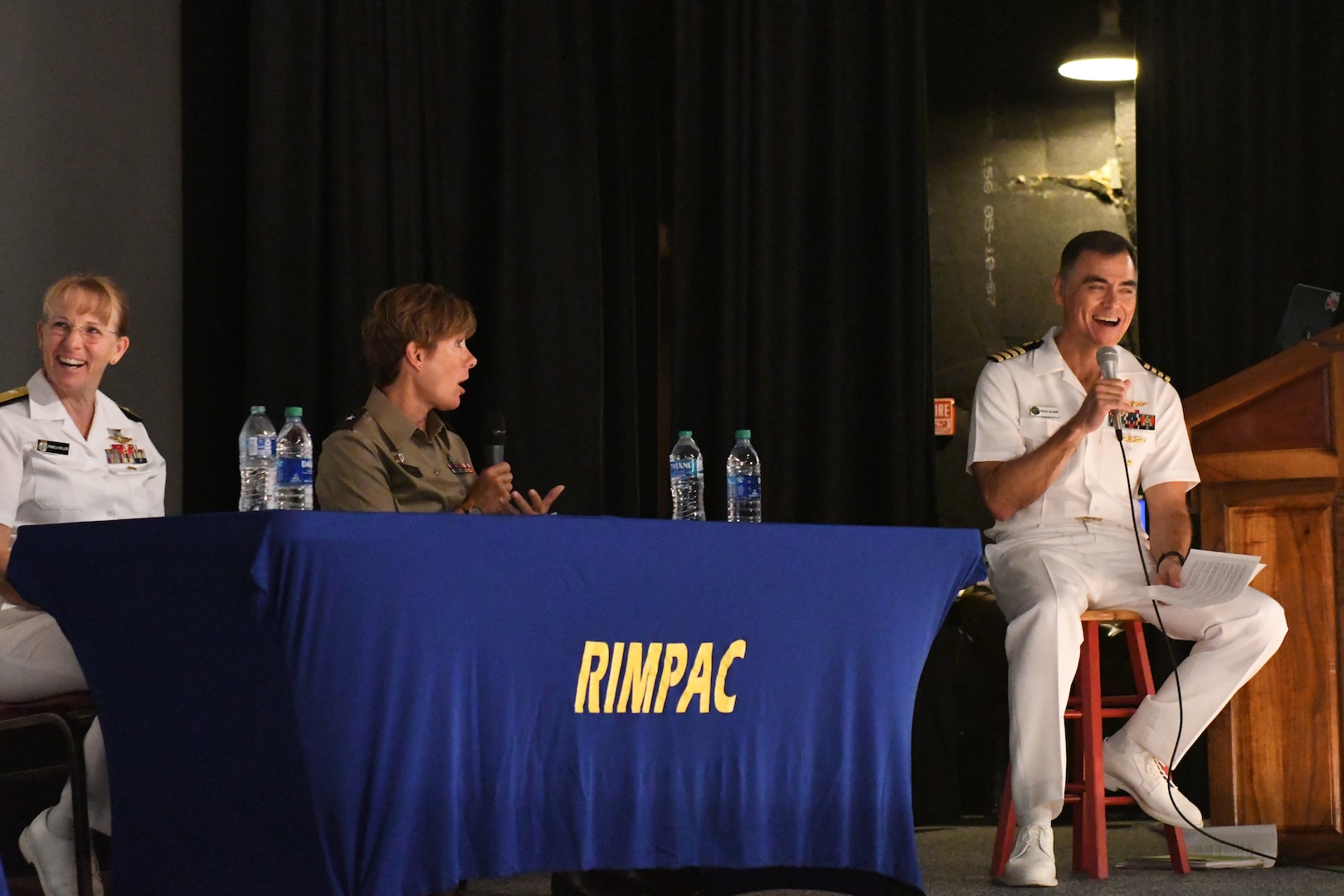 Panel of medical officers sit at a table on stage.