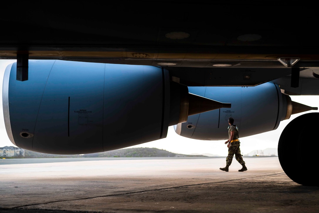 An airman walks underneath a parked aircraft.