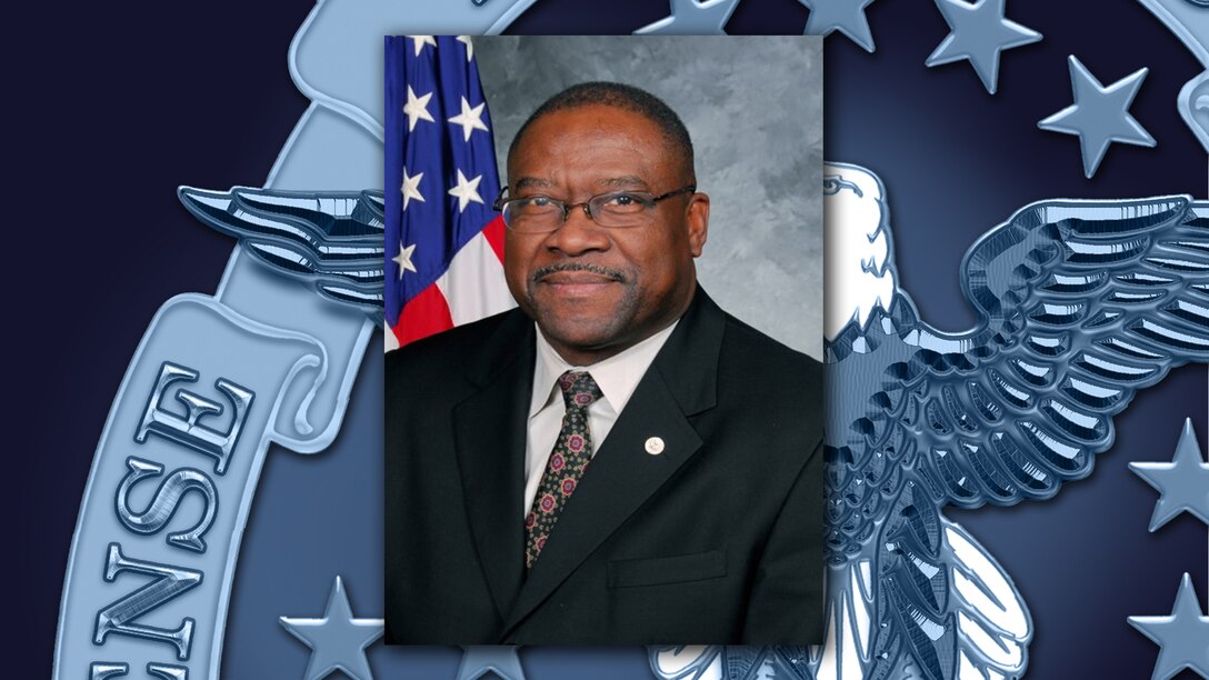 Head and shoulders picture of a black man in a white shirt and dark suit.