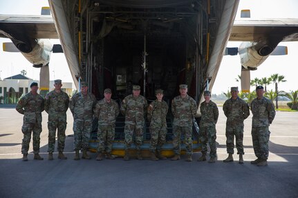 Several soldiers pose in front of the tailgate of a c-130 Aircraft