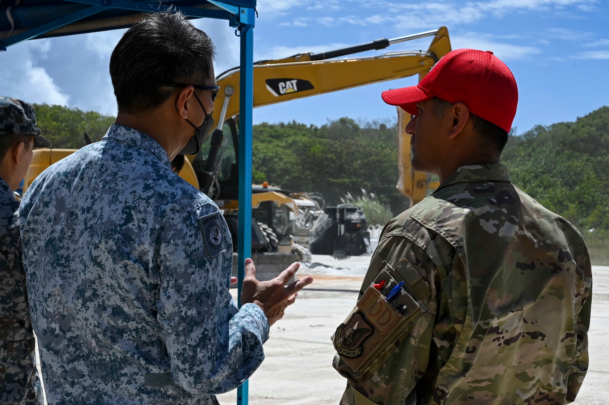 A U.S. Air Force Airman assigned to the 36th Wing, speaks with a member from the Republic of Singapore Air Force during the Pacific Unity Multi-Lateral Civil Engineer Key Leader Engagement, June 23, 2022 at Andersen Air Force Base, Guam. Senior military leaders from six Indo-Pacific nations gathered for the KLE to focus on multi-lateral efforts accelerating interoperability among their respective engineers.  (U.S. Air Force Photo by Airman 1st Class Emily Saxton)