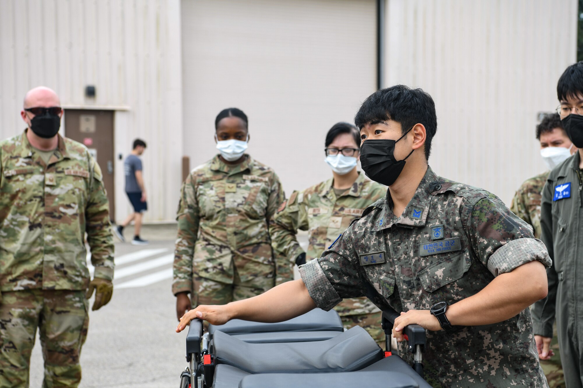 Republic of Korea Air Force Tech. Sgt. Mo Seh Yang, ROKAF Medical Group emergency medical technician, demonstrates using a litter carry, at Kunsan Air Base, Republic of Korea, July 19, 2022. The 8th Medical Group held a bilateral immersion training with ROKAF to exchange litter carrying and response techniques to further improve their interoperability. (U.S. Air Force photo by Staff Sgt. Sadie Colbert)