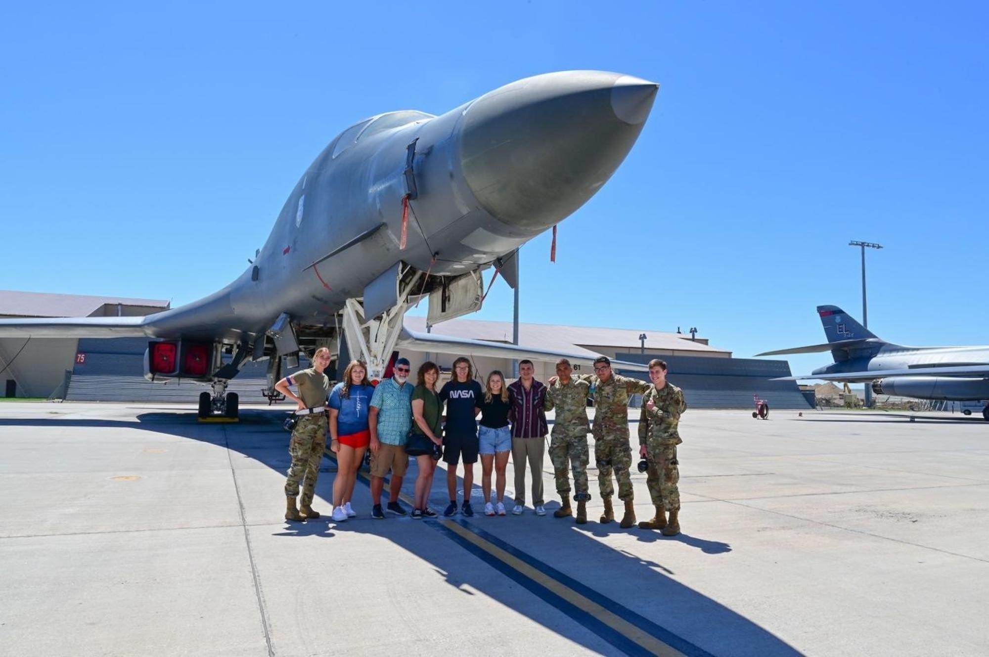 Airmen from the 28th Maintenance Squadron Fabrication Flight Non-Destructive Inspection lab pose for a photo with Marvin Pepper and his family under a B-1B Lancer at Ellsworth Air Force Base, S.D., July 13, 2022.