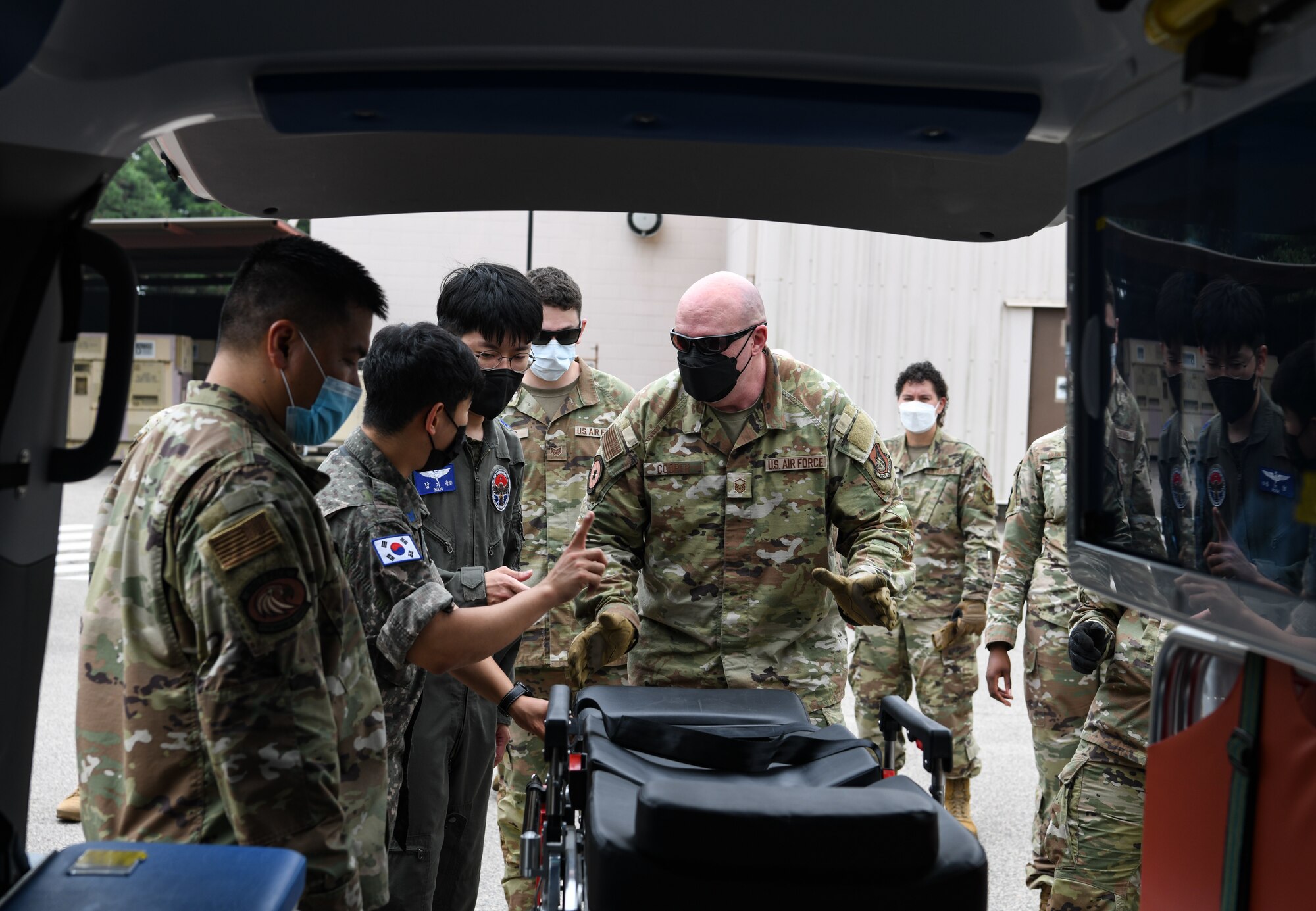 Republic of Korea Air Force medical members show U.S. Air Force Master Sgt. Jonathan Cooper, 8th Medical Operations Squadron mental health flight chief how to load a litter into an ambulance truck, at Kunsan Air Base, Republic of Korea, July 19, 2022. The 8th Medical Group held a bilateral immersion training with ROKAF to exchange litter carrying and response techniques to further improve their interoperability. (U.S. Air Force photo by Staff Sgt. Sadie Colbert)