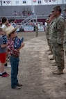 A young boy prepares to hand an American flag to a soldier.