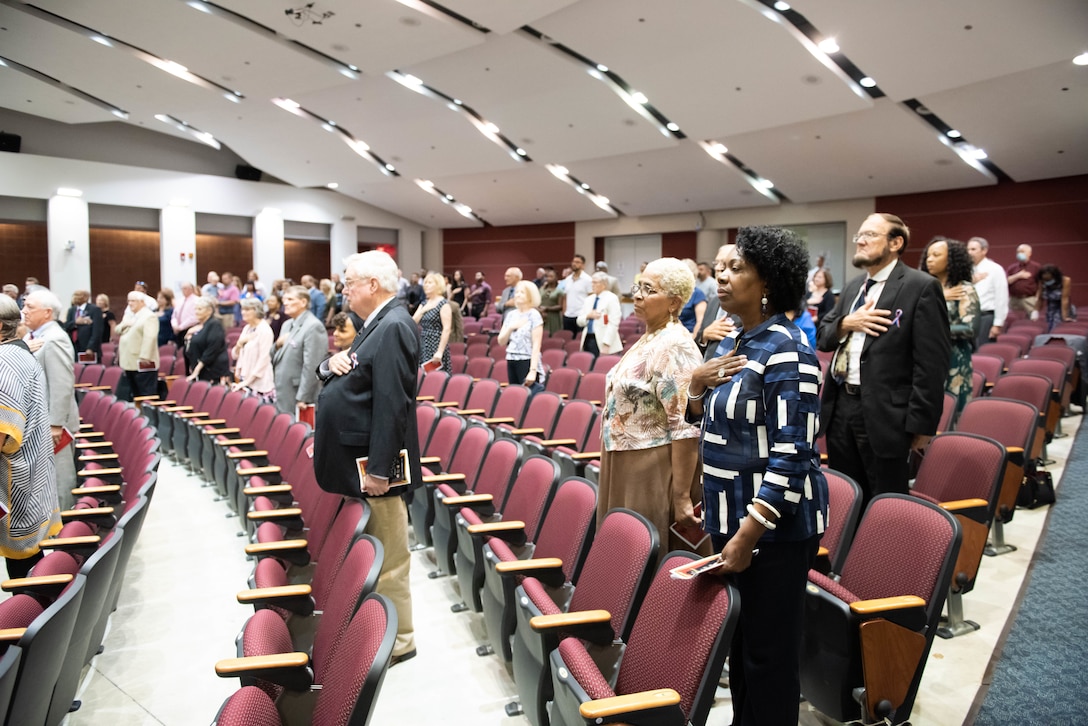 About 30 people standing in a auditorium.