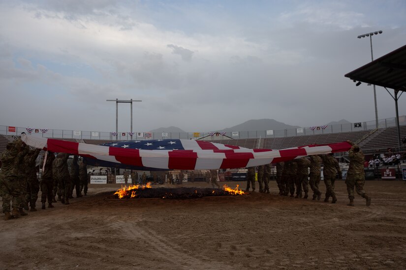 An American flag is draped over a fire during a flag retirement ceremony.