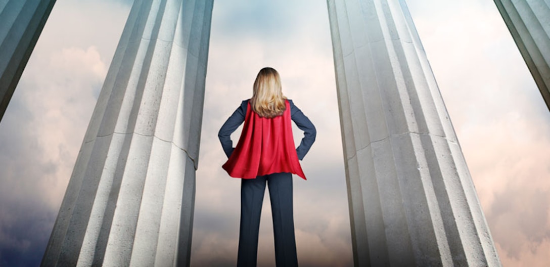 Back of a lady in a business suit with a red cape on.