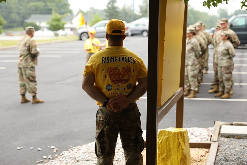 Warrant Officer Candidate Creighton Knopsnider looks on as Lt. Col. Tommy Guthrie, the commandant of the 166th Regiment Regional Training Institute, speaks with Warrant Officer Candidate School Class 22-301 at the class's sign, song, and hat ceremony at Fort Indiantown Gap, July 17, 2022. This ceremony is a tradition that originated in the 1950s that marks the class's advancement to the next phase of WOCS. (U.S. Army National Guard photo by Capt. Leanne Demboski)