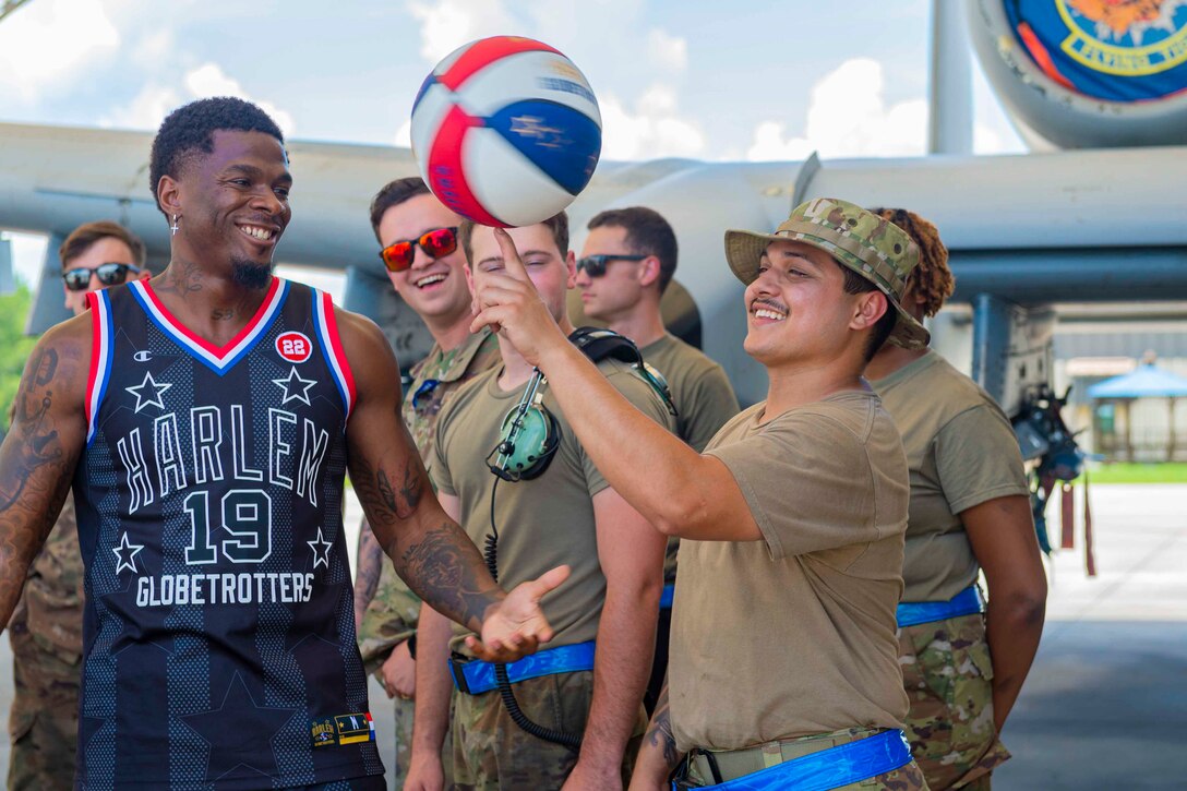 An airman spins a basketball on his finger as others watch.